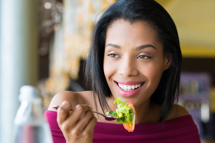 woman smiling holding a fork with salad