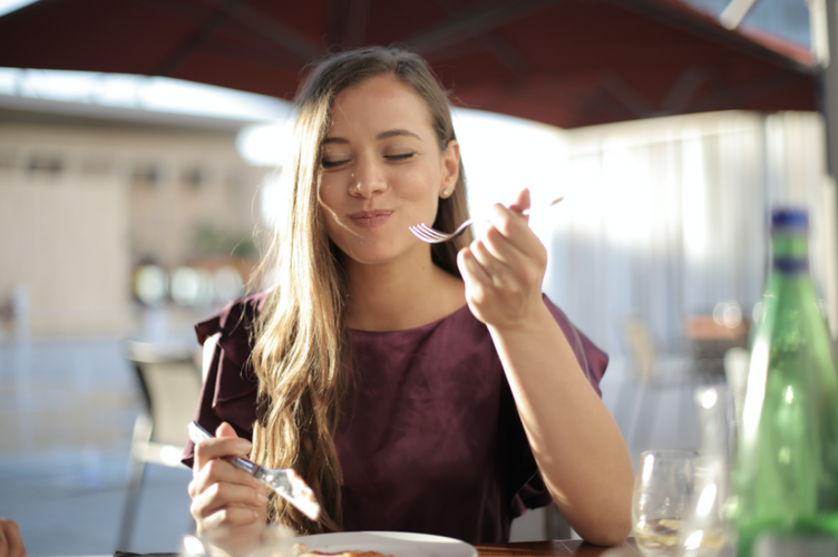 Woman eating and smiling while sitting at a restaurant
