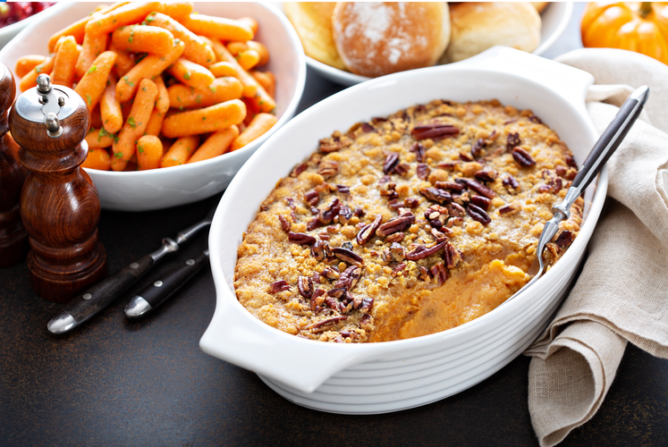 Sweet potato casserole and pepper mills on a table.
