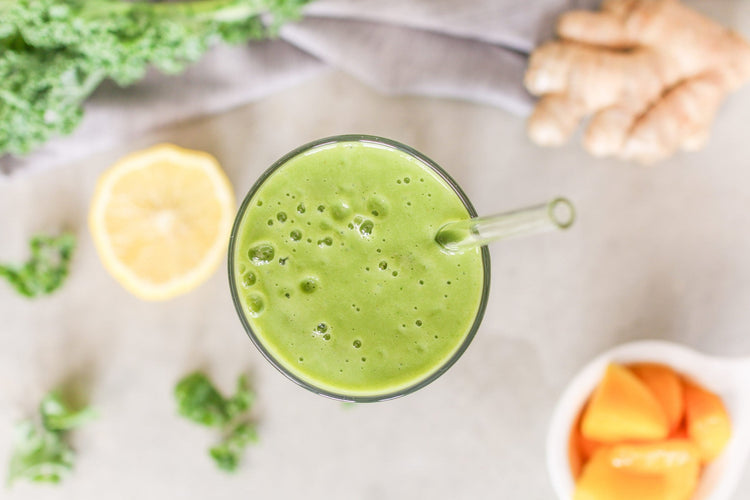overhead view of Kale Mango smoothie with ginger sliced mango and lemon