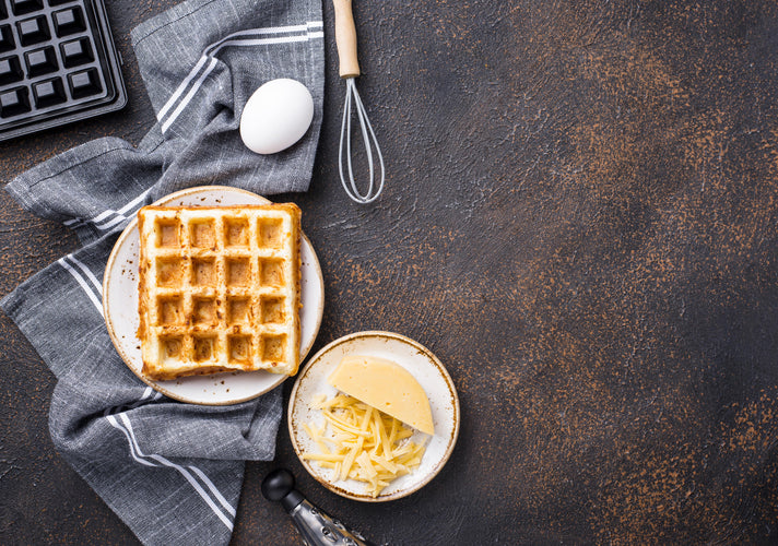 keto waffle with cheese egg and waffle maker on dark background