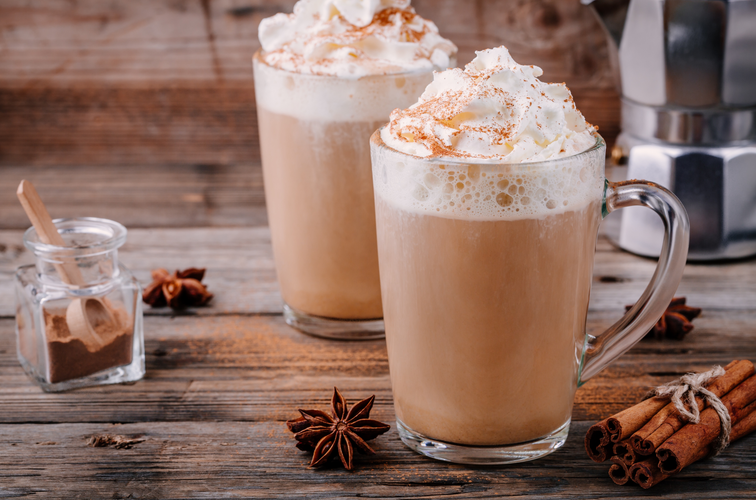 salted caramel shake with whipped cream and cinnamon in glass on wooden background