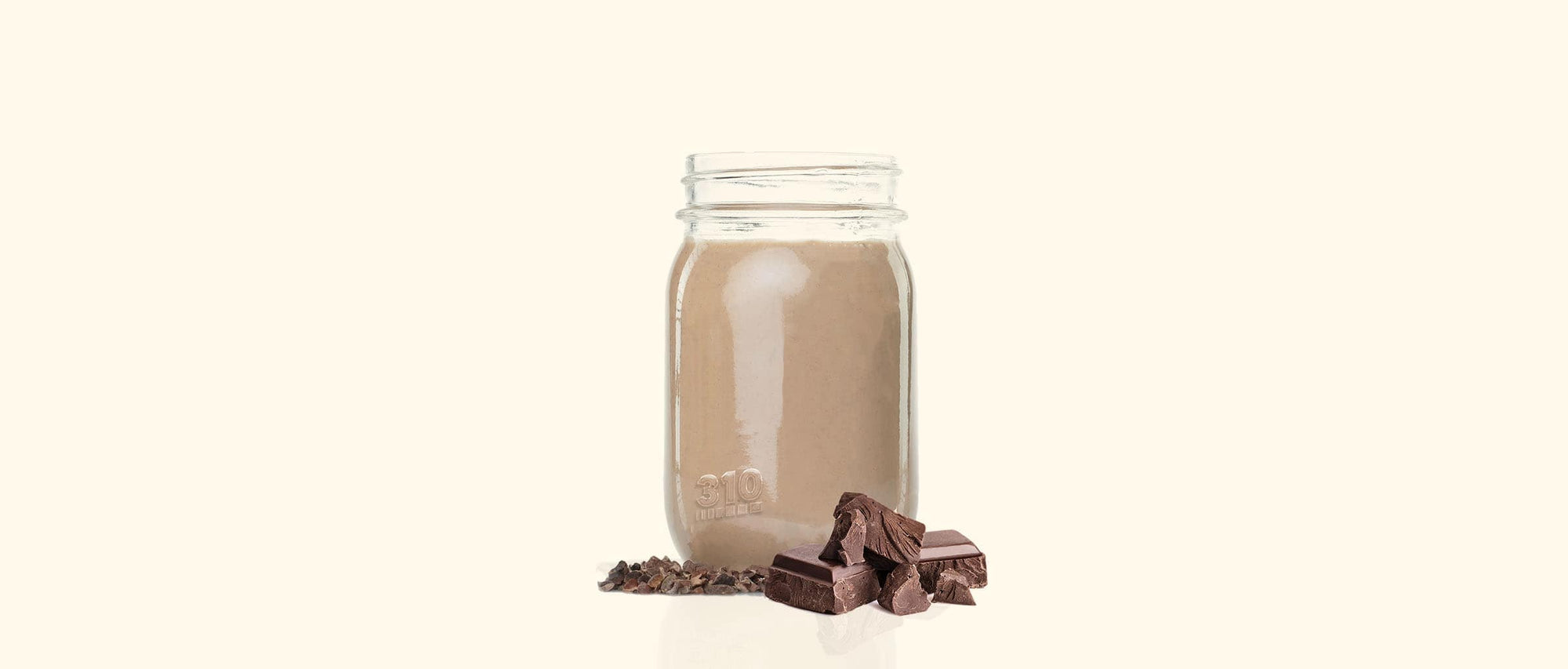 A 310 mason jar filled with a chocolate shake with chocolate pieces.