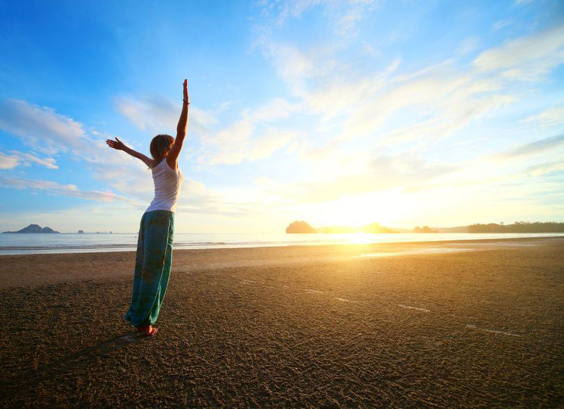 woman doing yoga at the seashore in direct sunlight