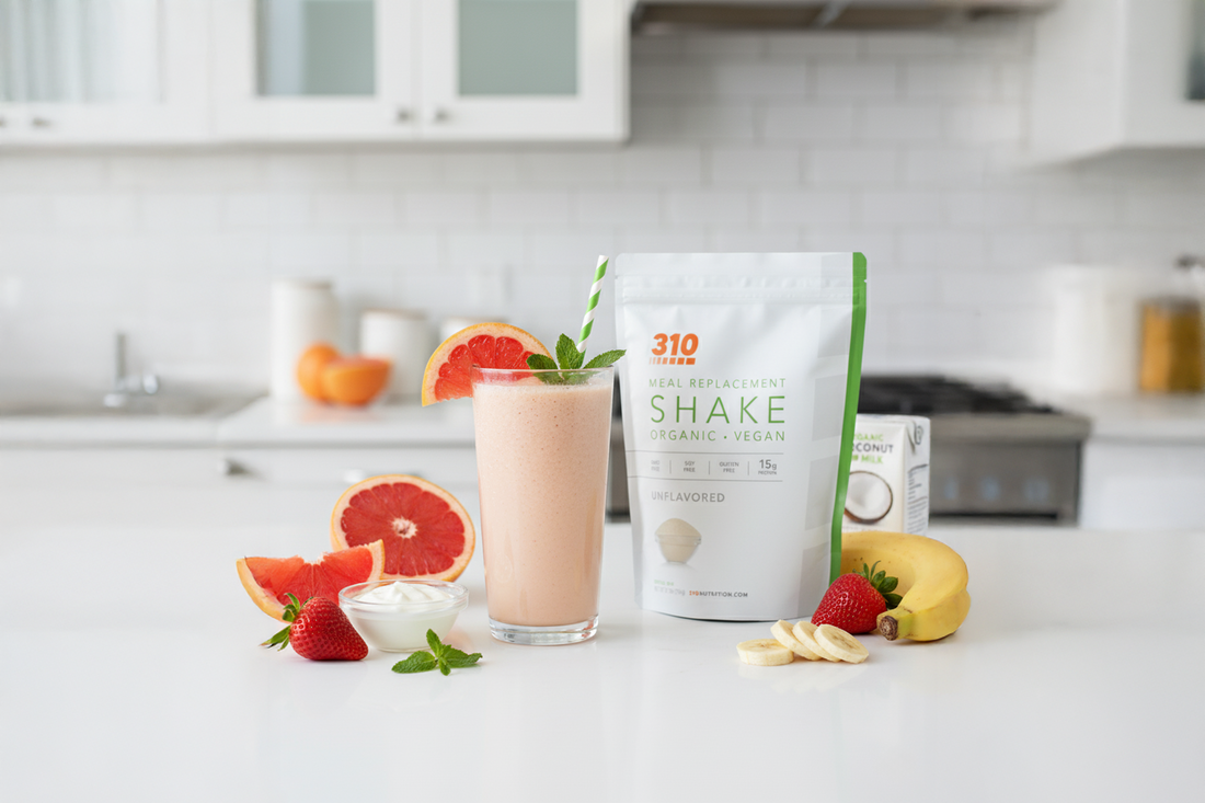 Glass of grapefruit smoothie with 310 Shake pouch, banana, strawberries, and fresh grapefruit.