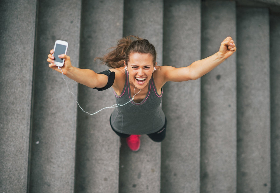 a woman in the stairs holding her phone with fitness app