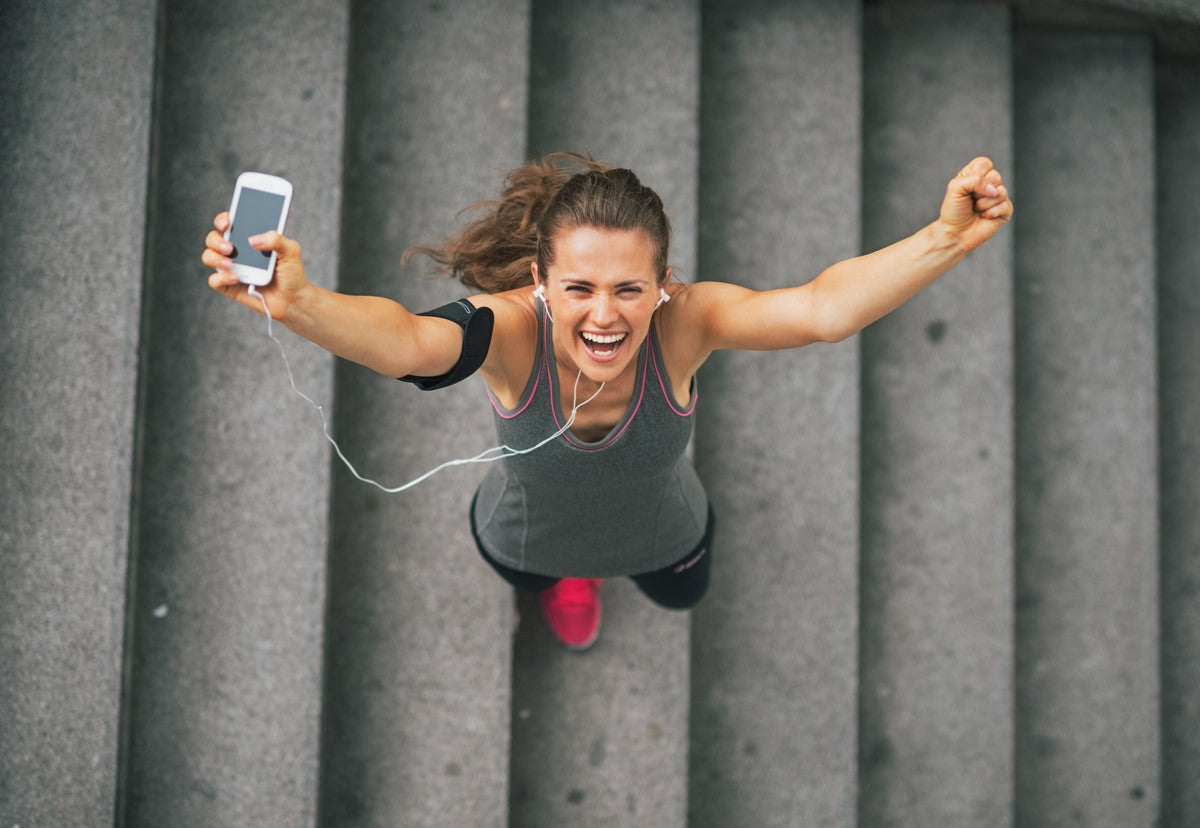a woman in the stairs holding her phone with fitness app