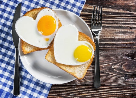 a plate of two bread and a heart shaped egg in a wooden surface