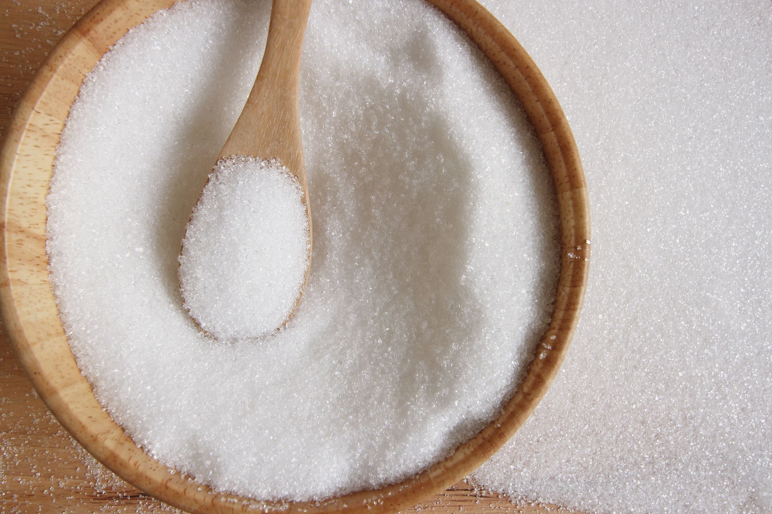 wooden bowl and spoon full of white sugar