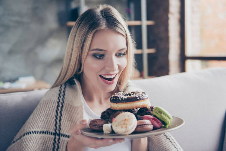 an amazed woman holding a plate full of dessert 