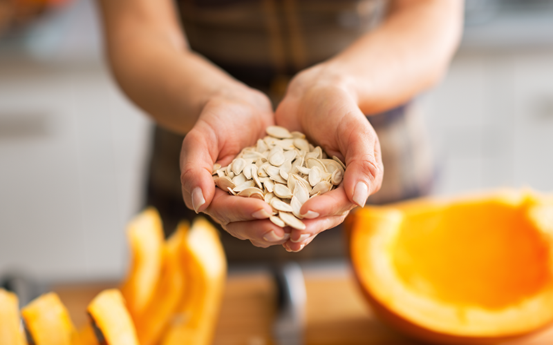 Shelled raw pumpkin seeds in dish on white table
