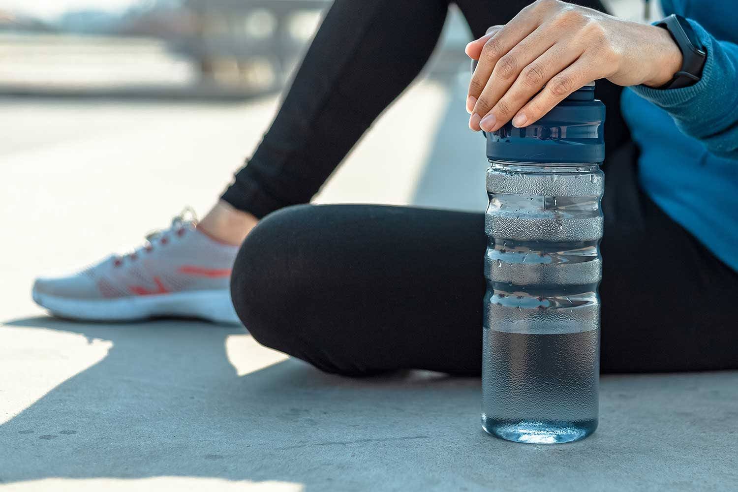 a woman sitting on the ground holding a water bottle