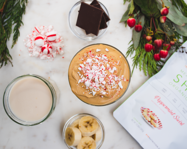 peppermint swirl on marble backdrop with almond milk, banana, peppermint candy, chocolate and protein powder