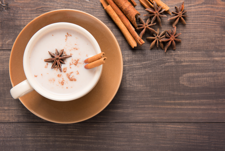 chai smoothie with spices in white mug on wood backdrop