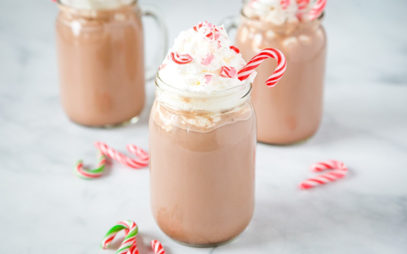 three white peppermint mocha shale topped with whipped cream and candy cane