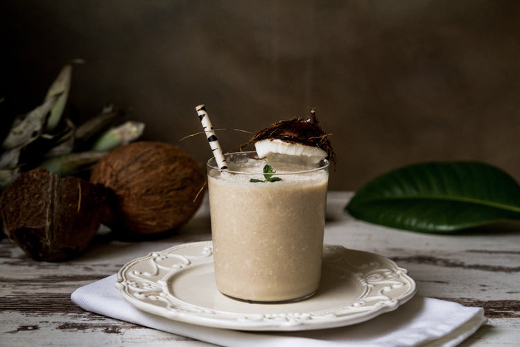 a glass of coconut cashew chip shake on a white plate