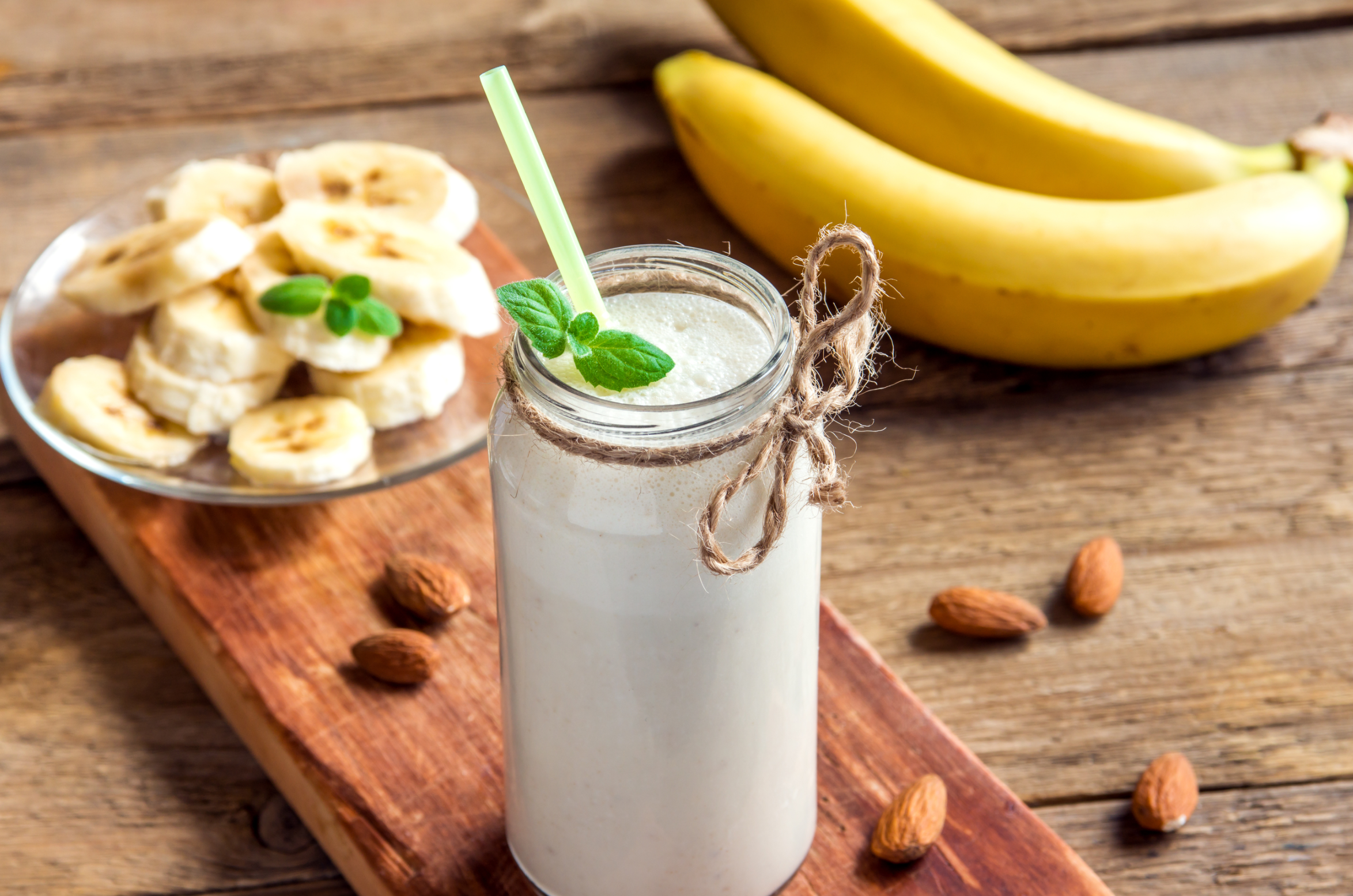 Banana smoothie with mint and almond over rustic wooden background
