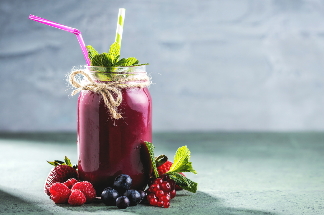Flat-lay of berry smoothie in mason jar with superfoods on concrete background.