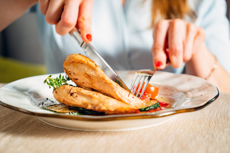 women cutting chicken cutlet 