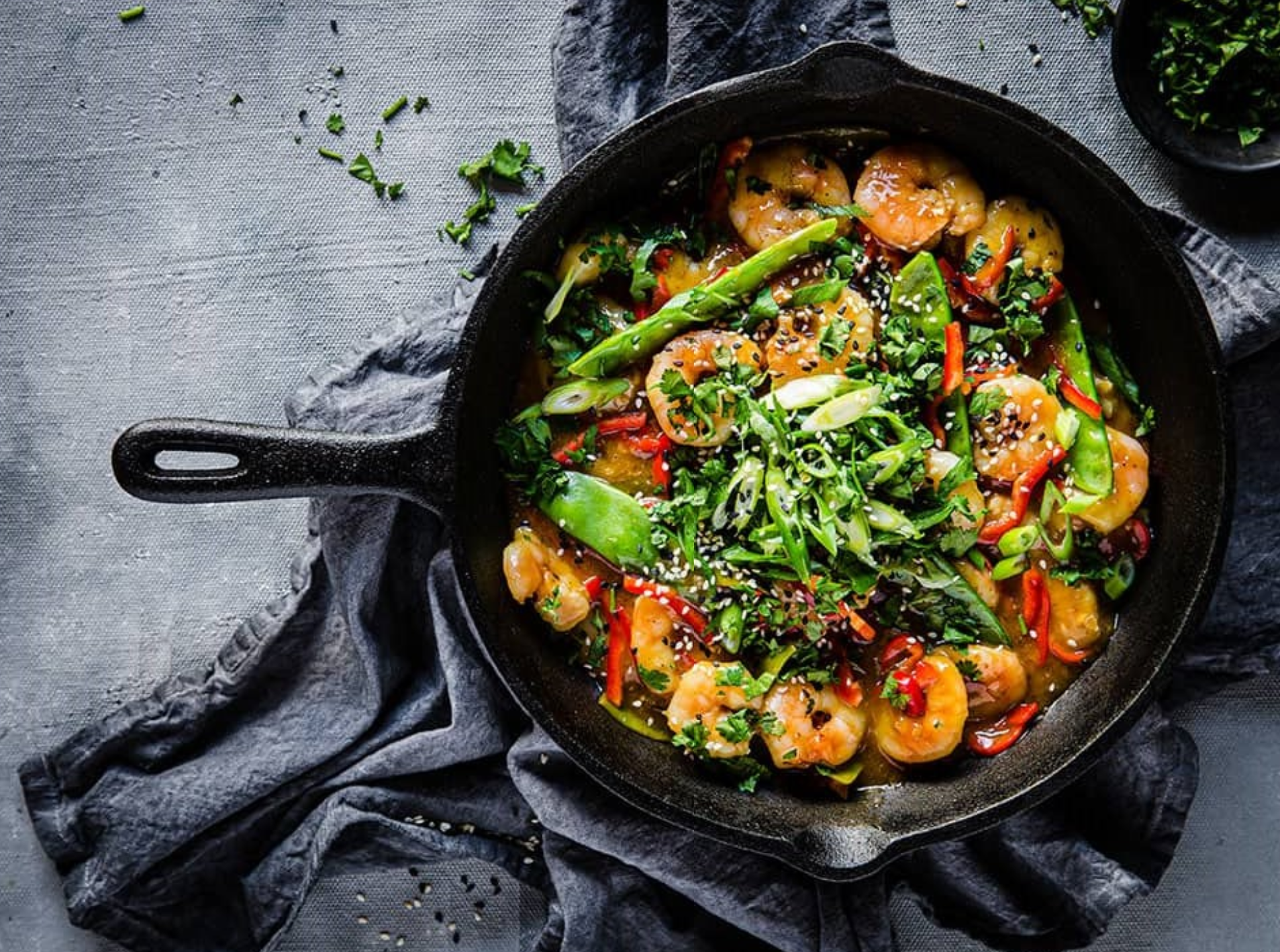 Keto shrimp stir fry with vegetables on dark grey background