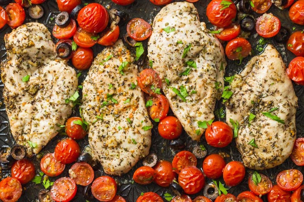Baked chicken Italian breasts seasoned with herbs, surrounded by cherry tomatoes 