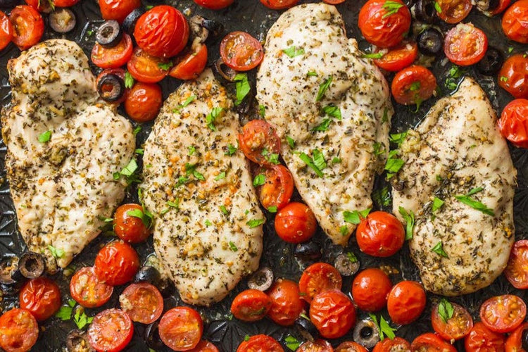 Baked chicken Italian breasts seasoned with herbs, surrounded by cherry tomatoes 