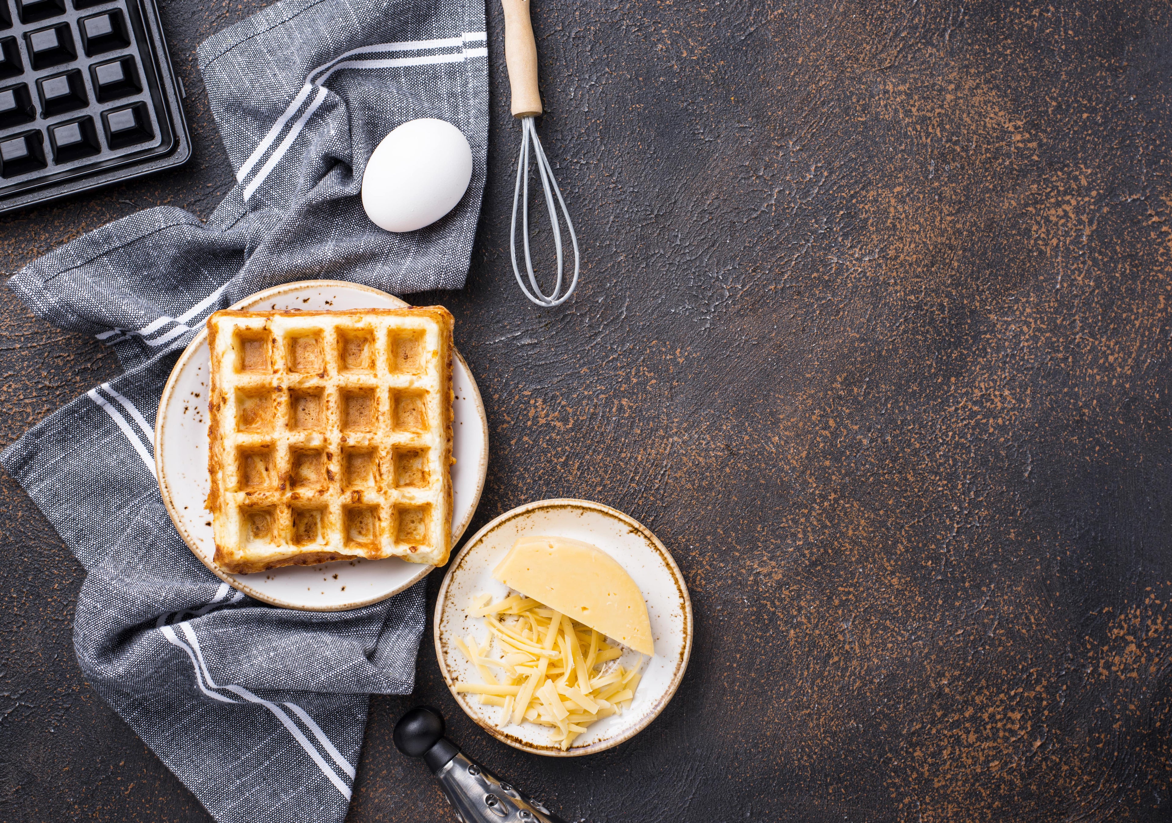 keto waffle with cheese egg and waffle maker on dark background
