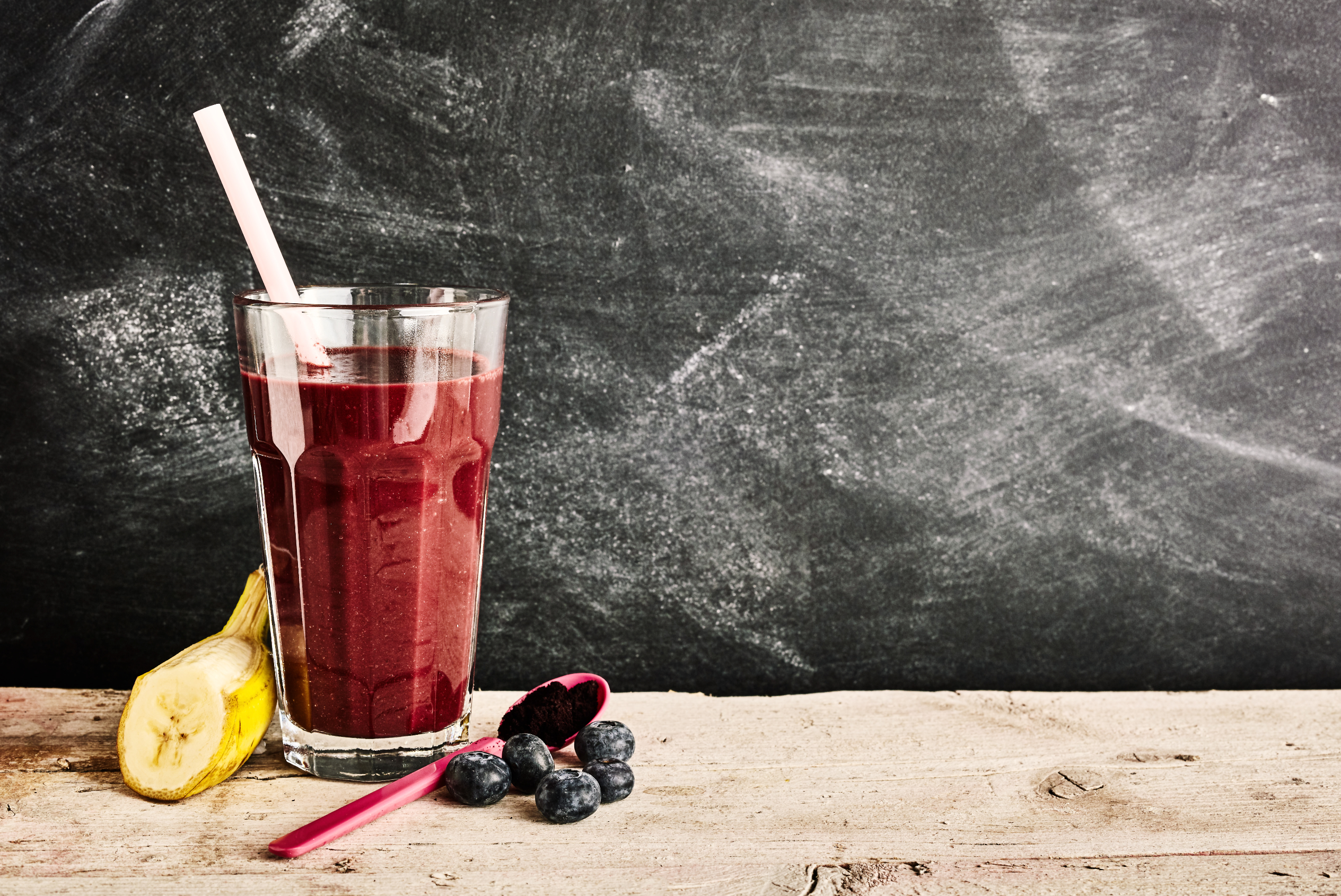 A glass of chocolate acai smoothie with sliced banana and berries