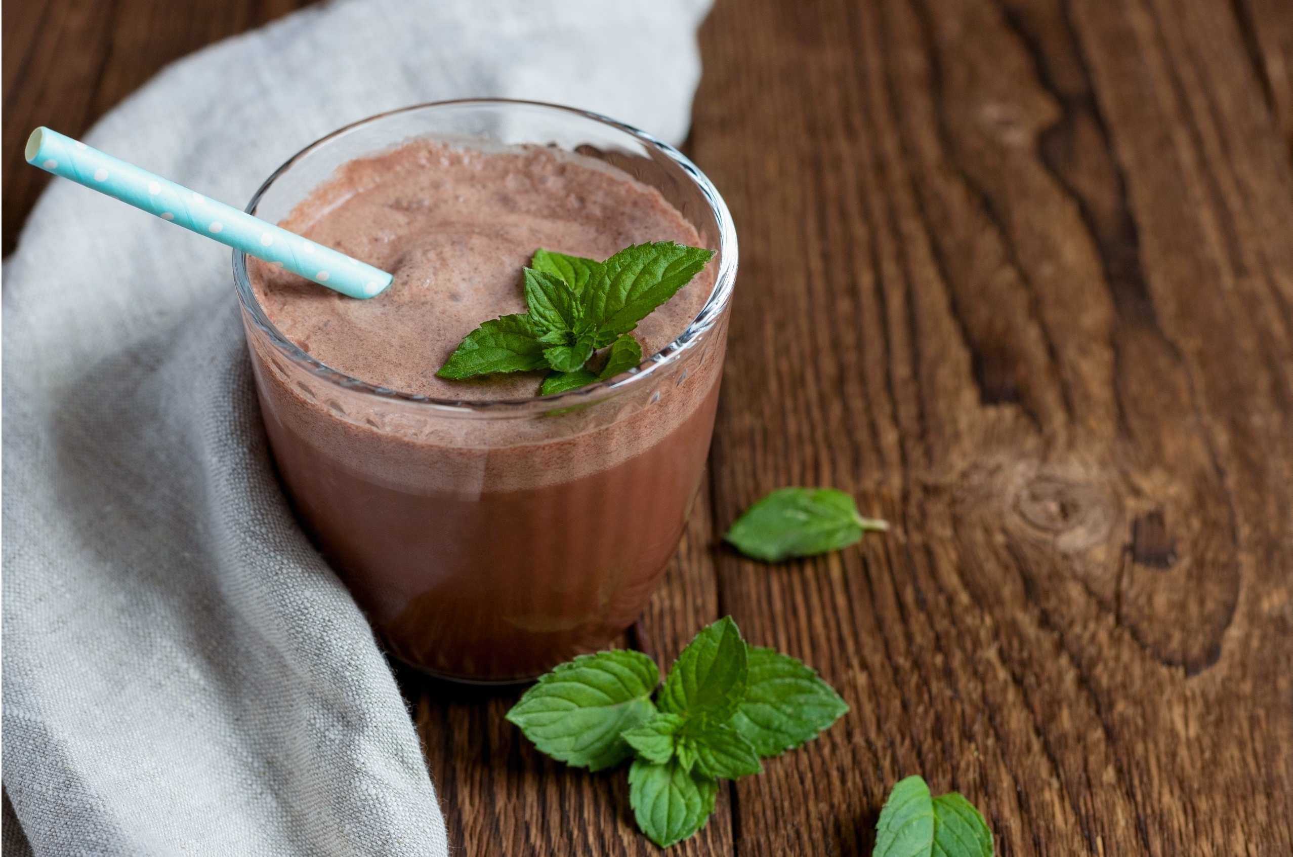 a glass of chocolate smoothie with mint leaves