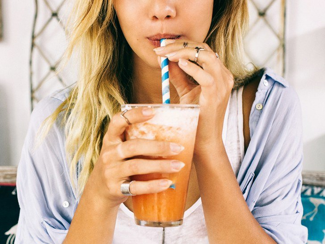 woman sipping in a glass of smoothie