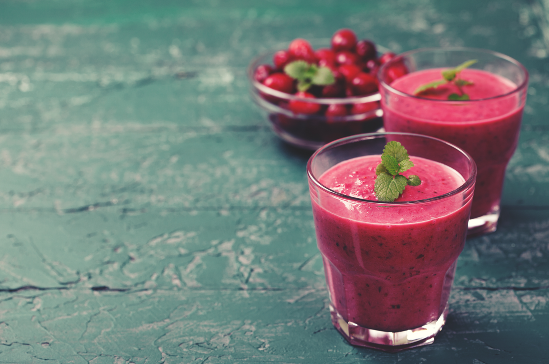cranberry smoothie in glasses against wood background