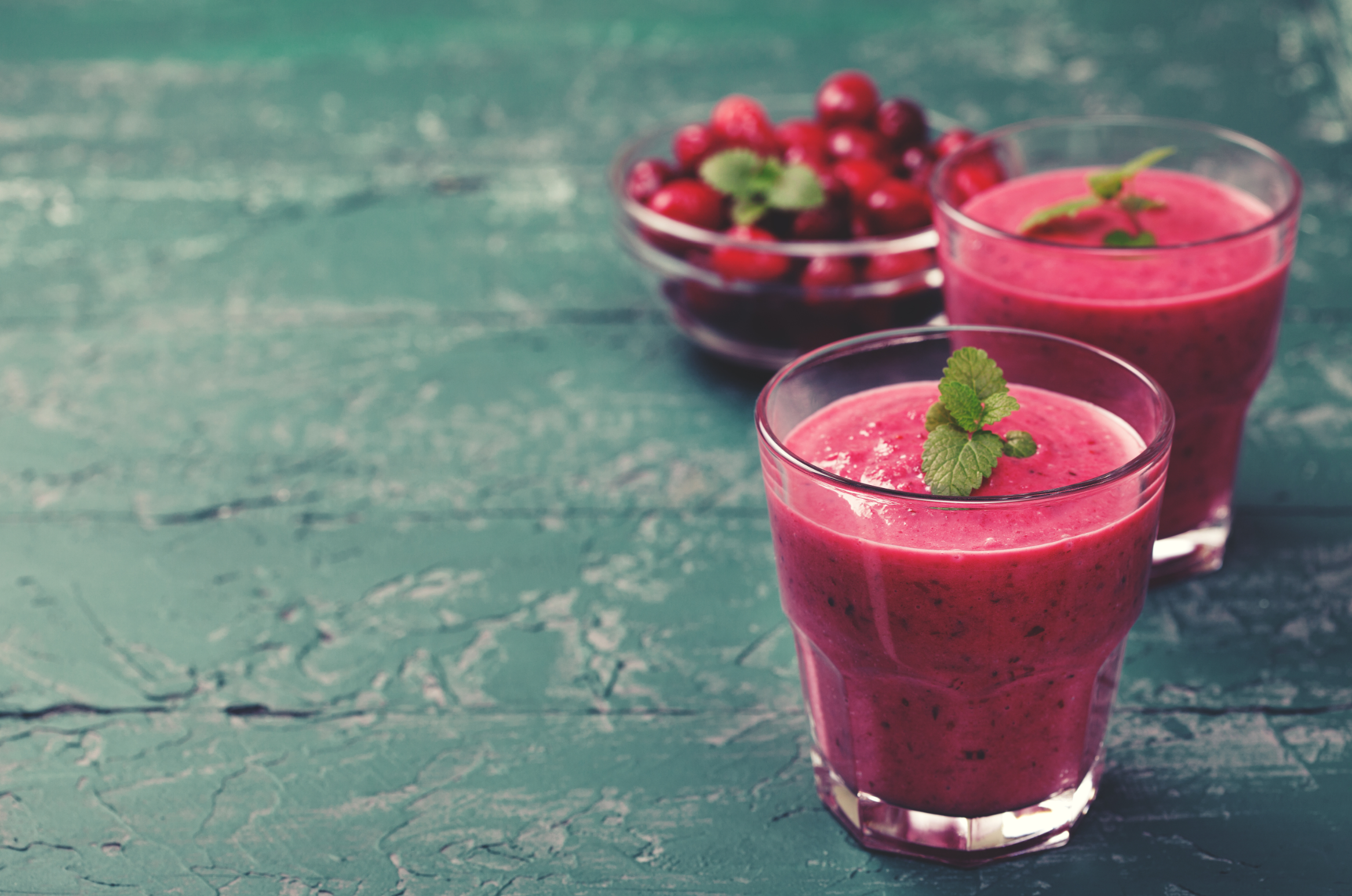 cranberry smoothie in glasses against wood background
