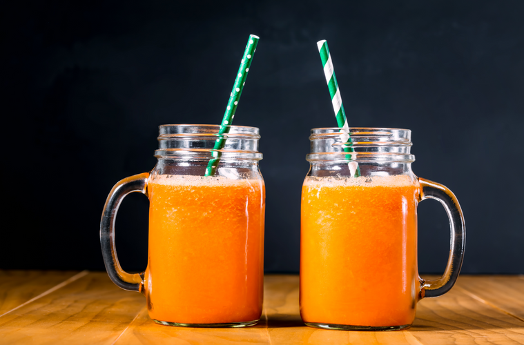 Carrot smoothies in masons jars on black