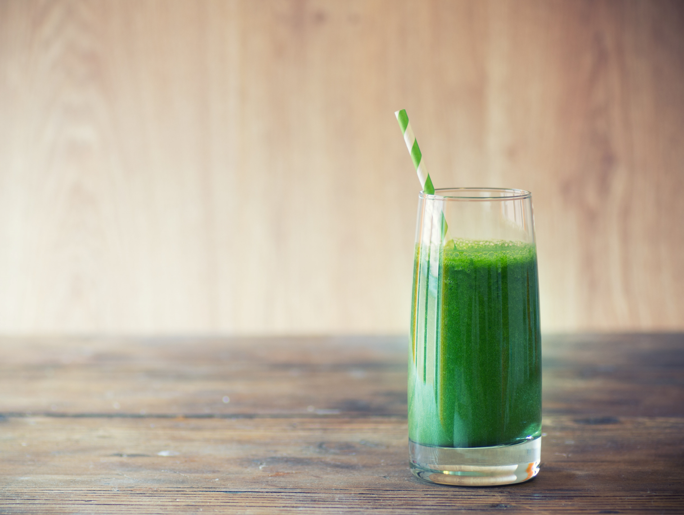 A tall glass of Cucumber Lemon Recovery Slushee with a wooden background