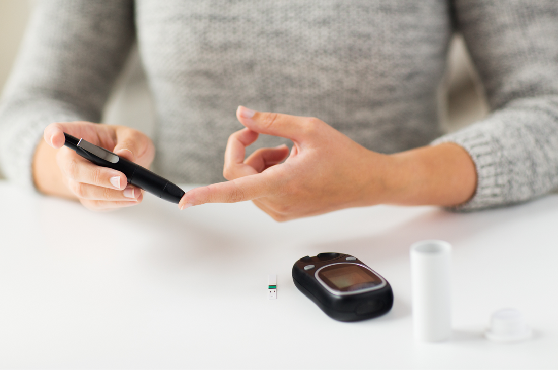 close up of woman checking blood sugar level by glucometer at home