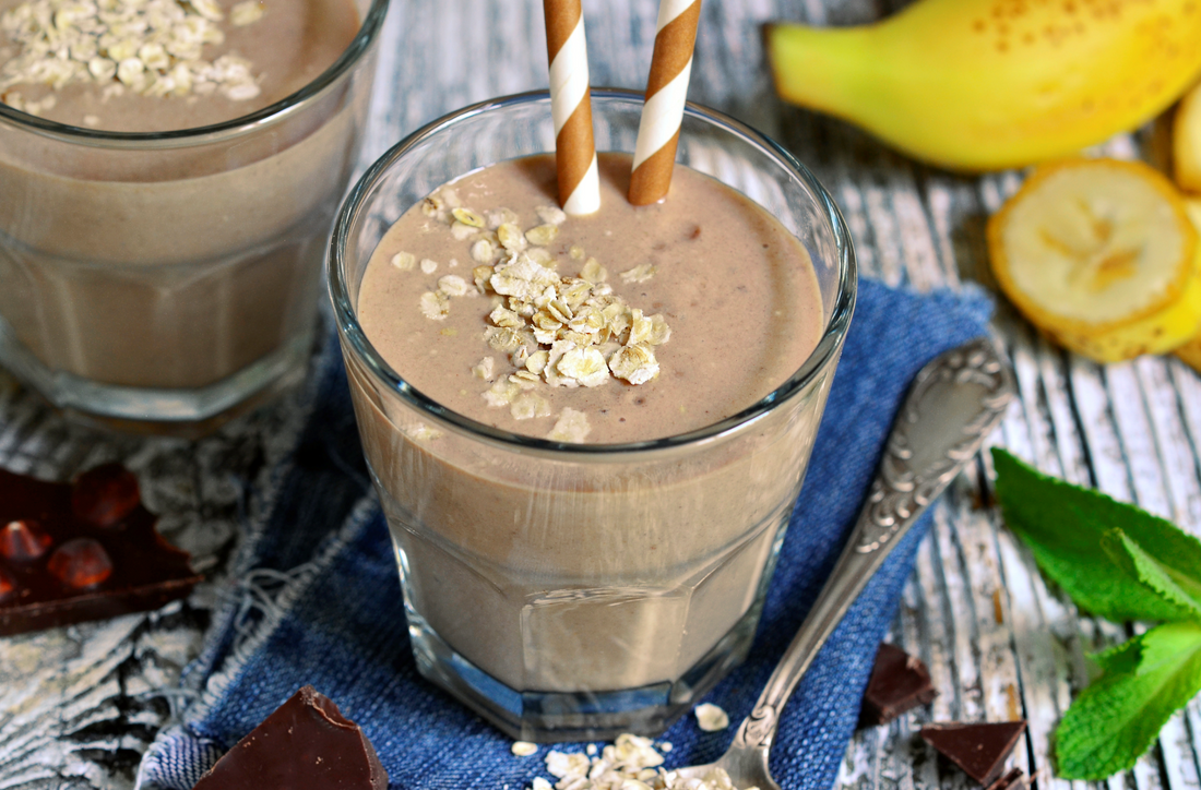 Chocolate and banana smoothie with oats in a glass on wooden table