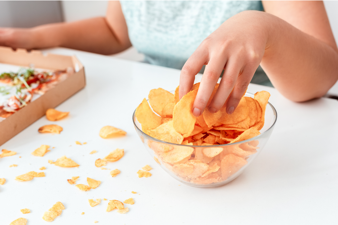 a bowl of chips and a hand picking 