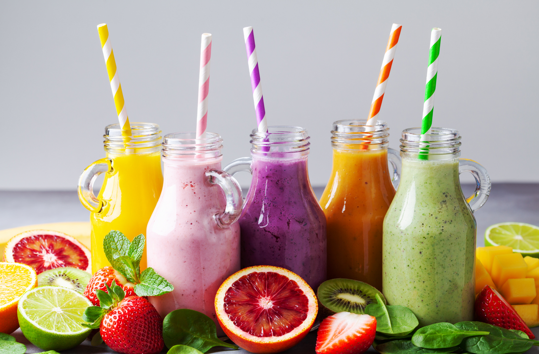 jars of different flavors of smoothies surrounded byfresh fruits