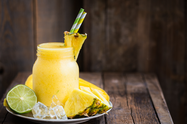 lemonade smoothie and sliced pineapples on a wooden board