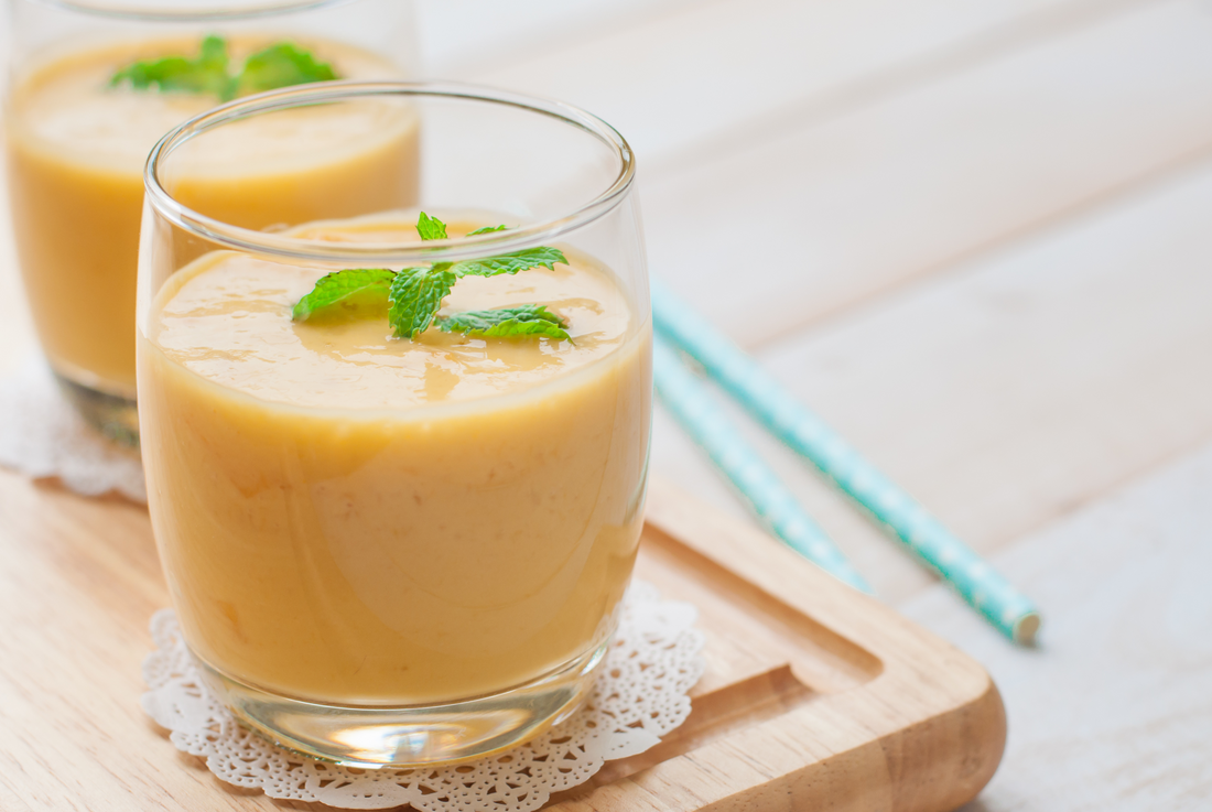 Healthy drink mango smoothies with mint on wooden background