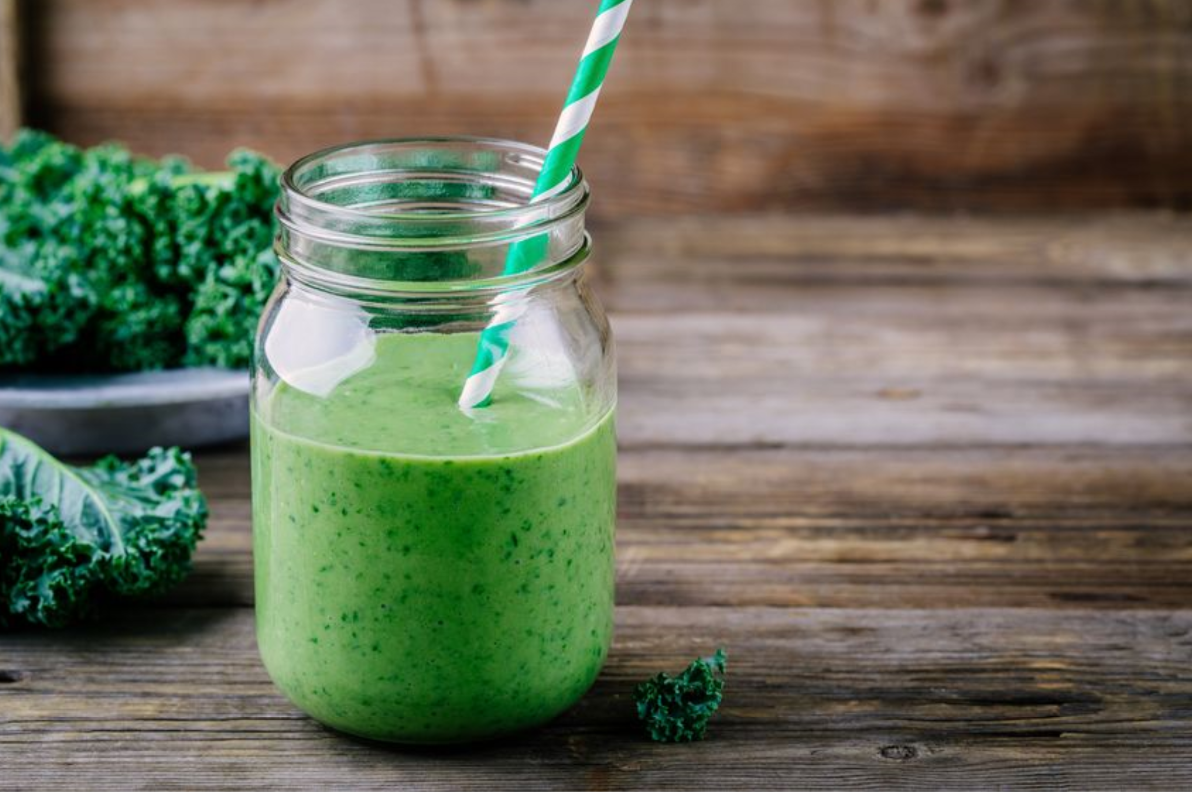 Healthy detox green smoothie with kale in mason jar on rustic wooden background