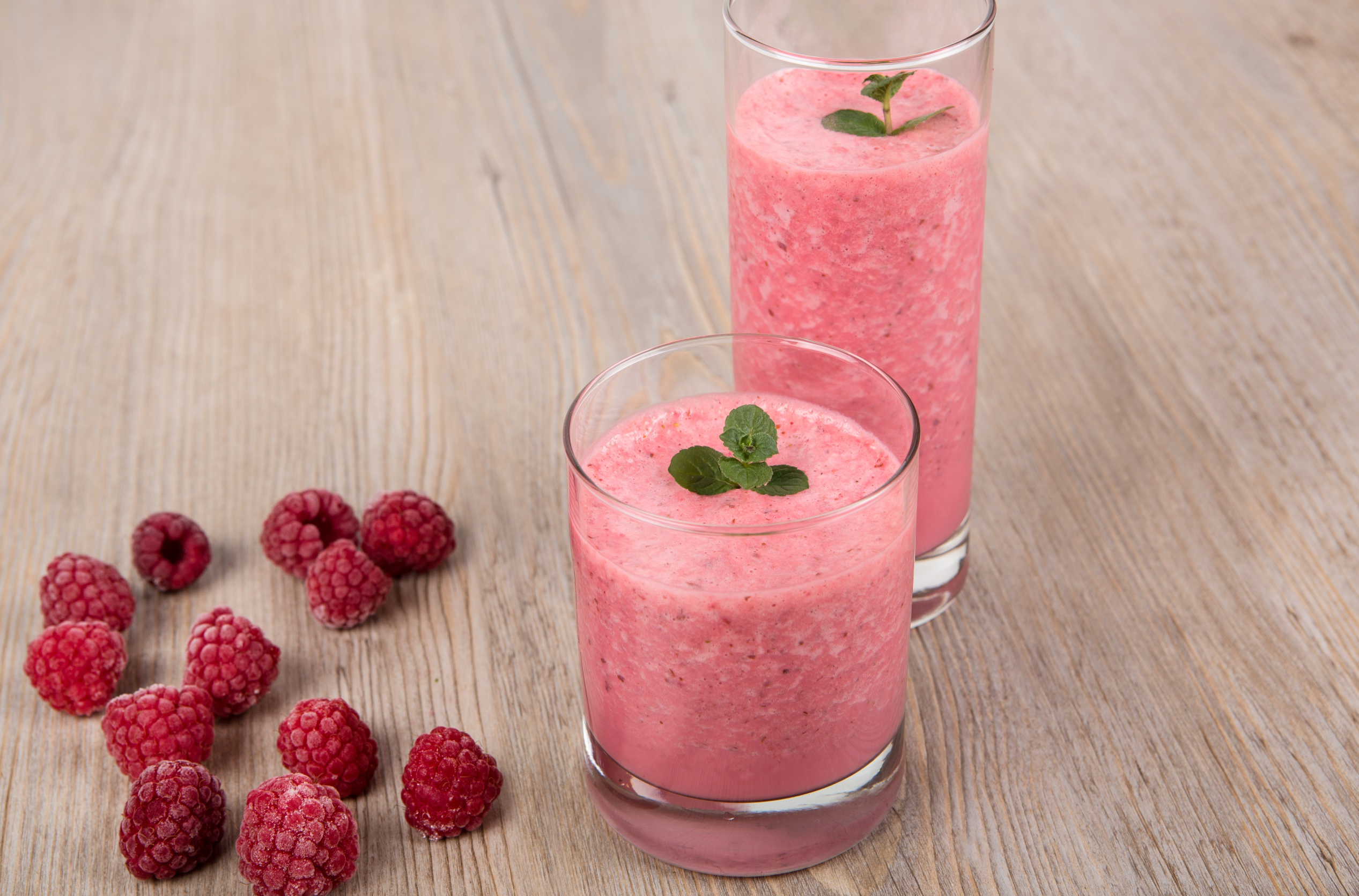 fresh berries and two glasses of smoothie in a wooden surface