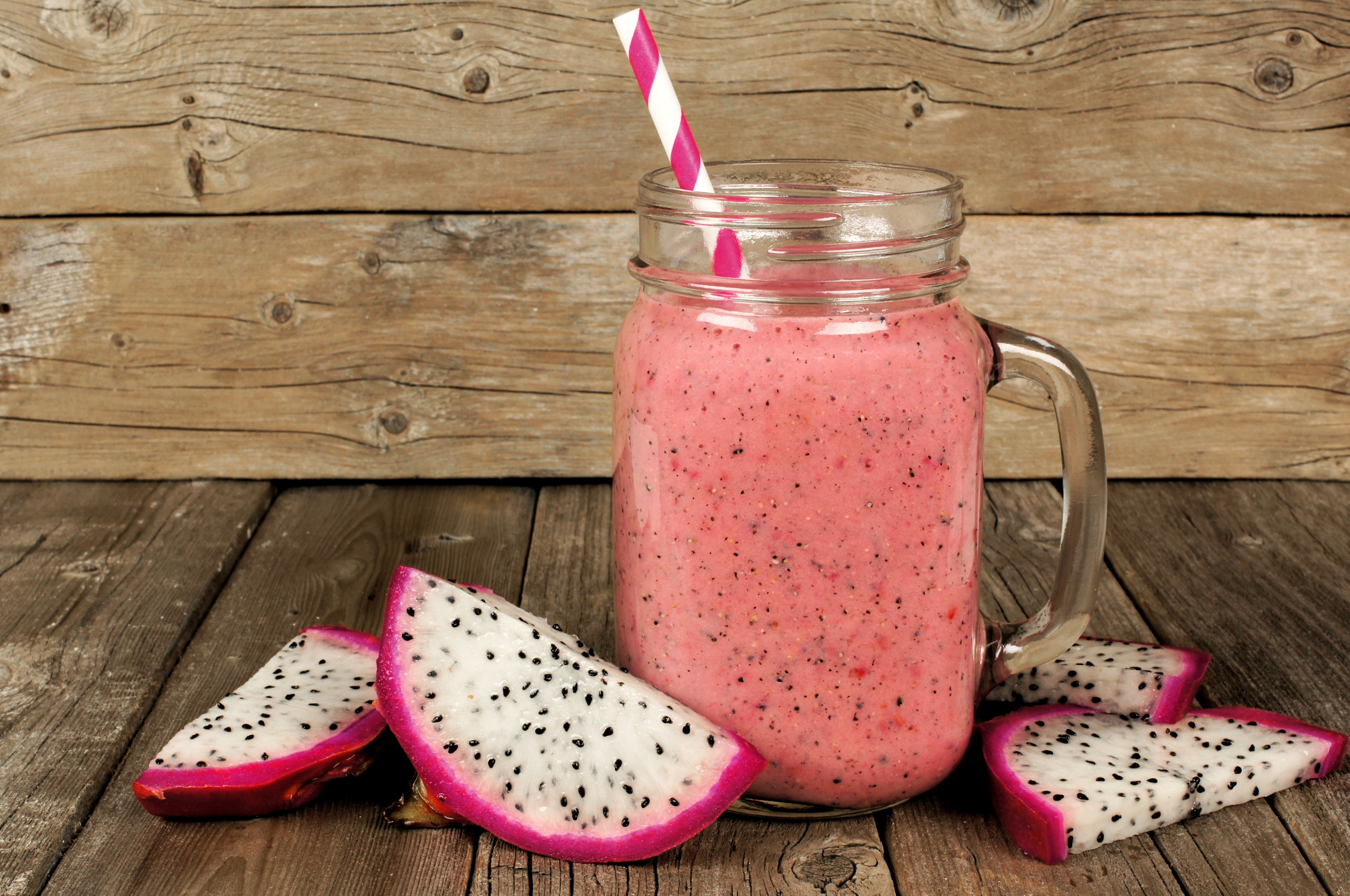  dragon fruit smoothie with fruit slices on an old wood background