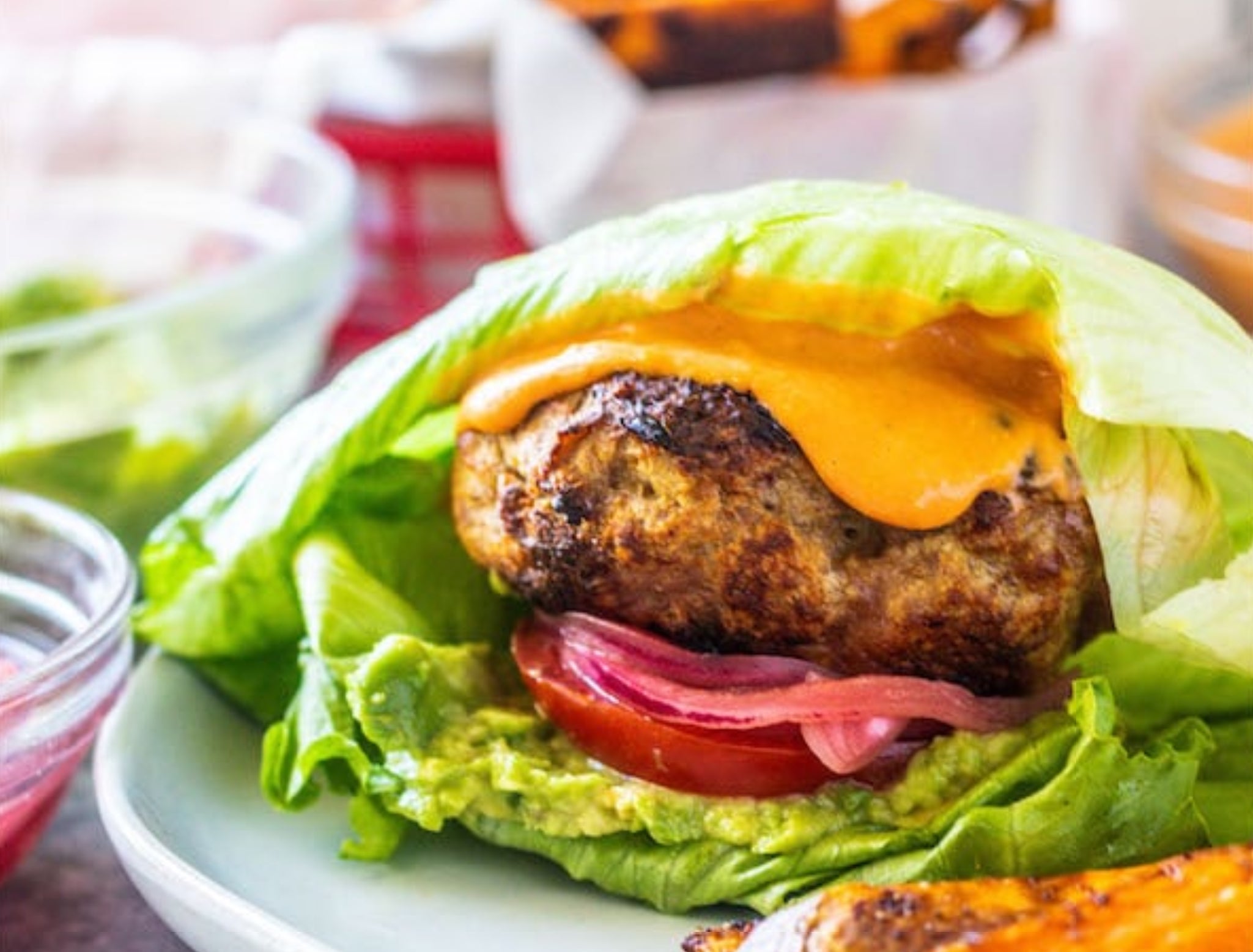 a plate of grilled turkey burger wrapped in lettuce
