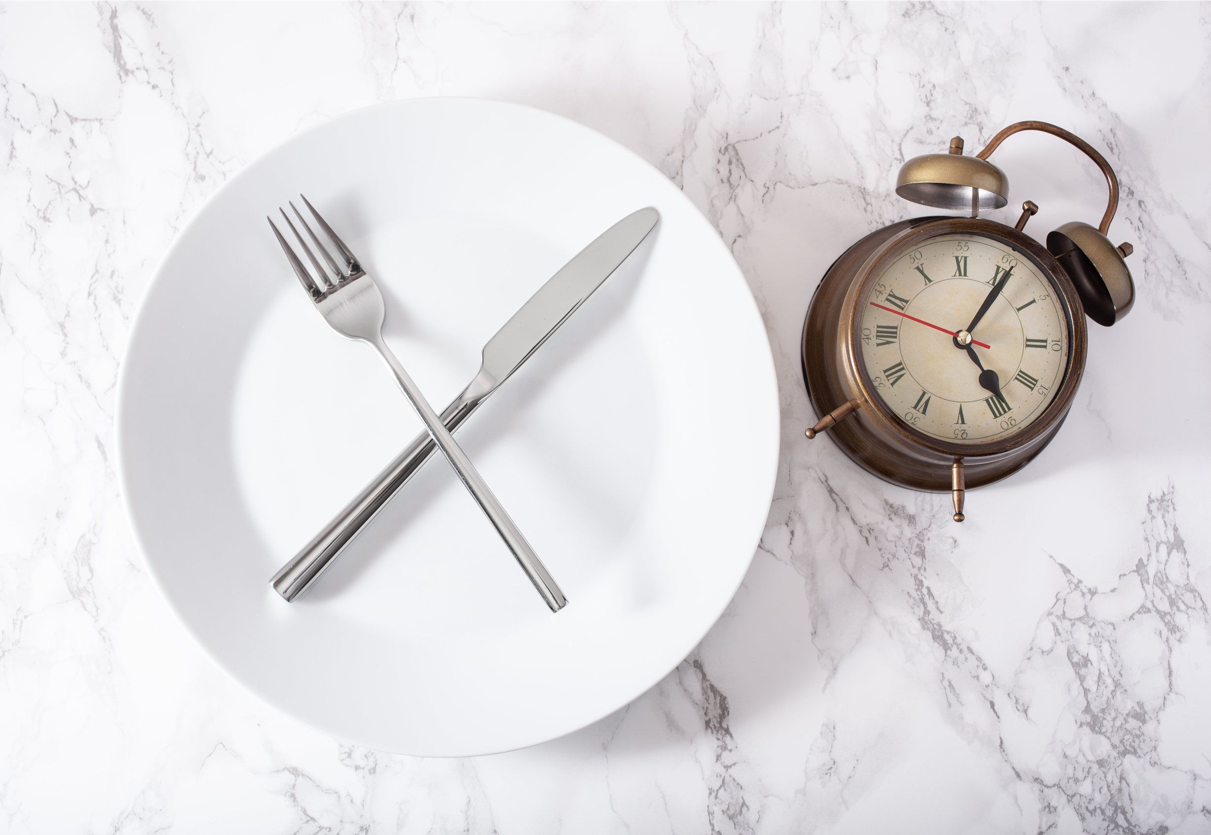 a white plate with knife and fork and clock 