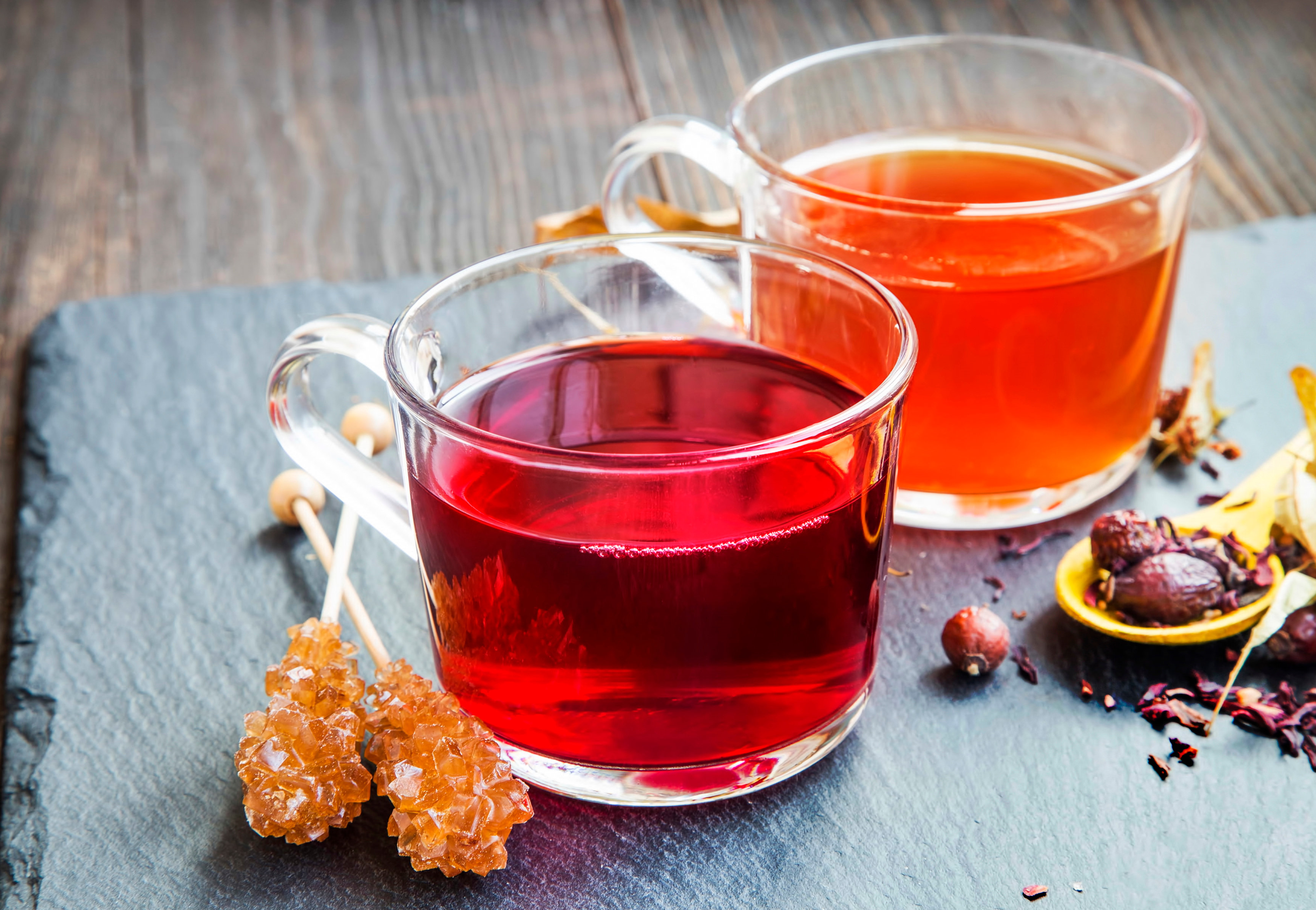 two clear mugs of orange hibiscus teas on a board