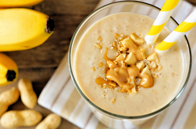banana smoothie in a glass with peanuts and peanut butter