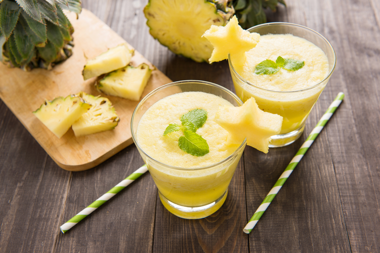 Pineapple smoothie with fresh pineapple on wooden table