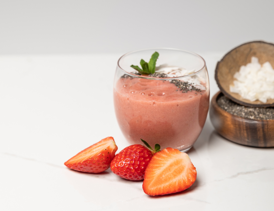 tasty smoothie with coconut flakes in glass near tasty strawberries on grey