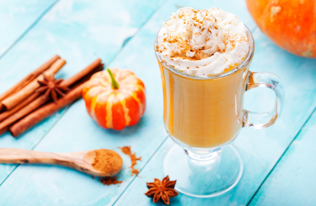 Pumpkin smoothie  with whipped cream on top on a turquoise wooden background
